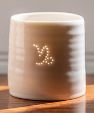 Load image into Gallery viewer, A ceramic porcelain tealight holder, with the Capricorn astrological symbol pierced into it with tiny holes, allowing candlelight to twinkle through. Natural glossy glaze, almost translucent. Horoscope, astrology, zodiac.