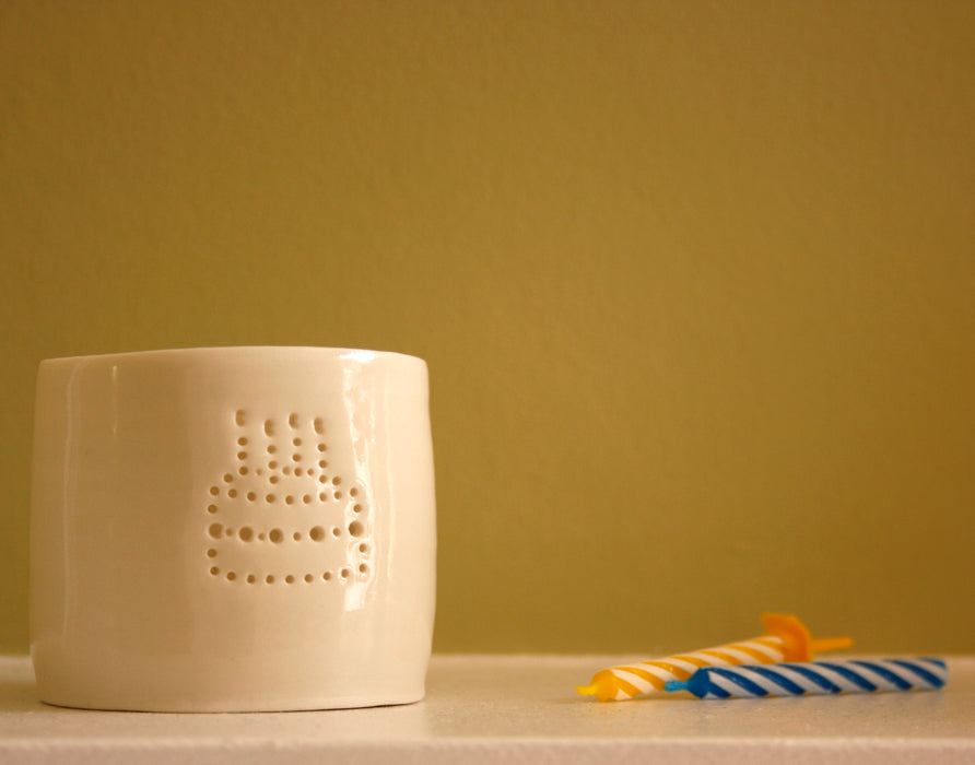 Porcelain ceramic tealight candle holder, featuring a design of a birthday cake with candles, natural glossy glaze. Birthday present. Celebration.