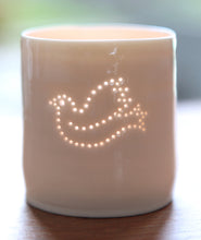 Load image into Gallery viewer, Symbol of peace, this porcelain tealight holder features a dove. Ceramic candle holder with a natural glossy glaze and gentle glow. Christmas decoration.