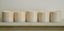Load image into Gallery viewer, A series of five handmade porcelain tealight holders. These ceramic candle holders spell out the word "dream". Small business. Relaxing candles.