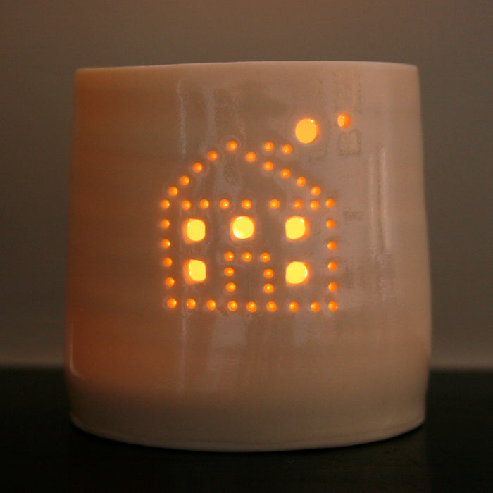 A cute house with smoke emerging from the chimney, pierced into a ceramic porcelain tealight candle holder. This candle votive will create a sense of home, hygge and warmth.