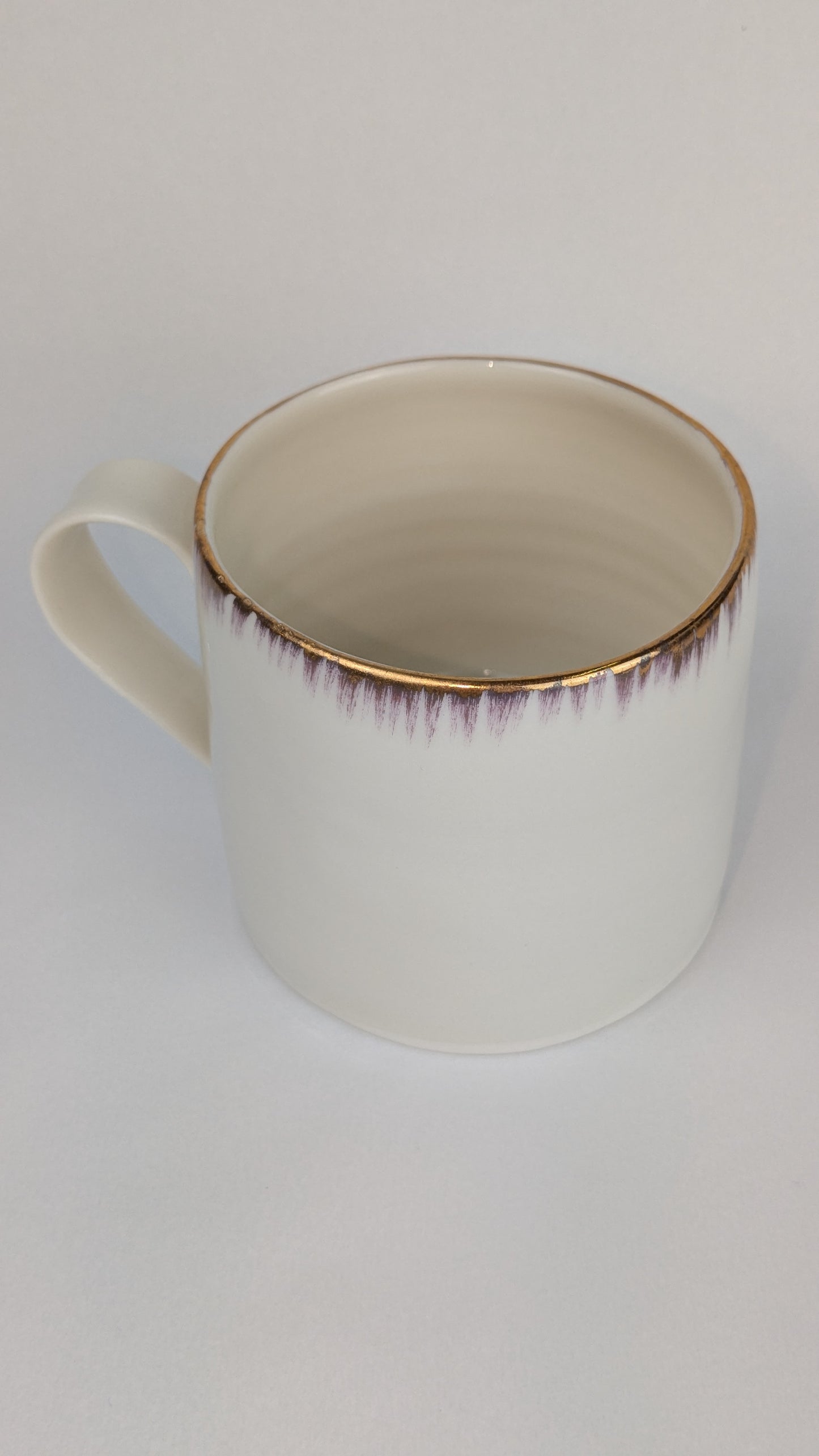 White mug with gold rim on a white background