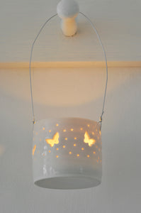 This hanging porcelain candle holder is good garden decoration. With little butterfly design, the ceramic tealight holder hangs on a wire for outdoor lighting.
