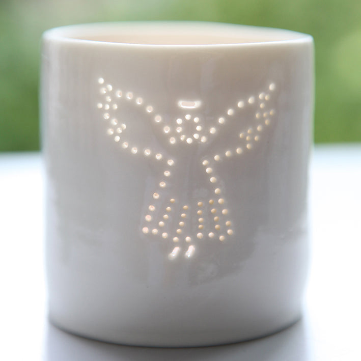 A photo of a ceramic porcelain tealight candle holder featuring a delicately pierced design of an angel with a halo