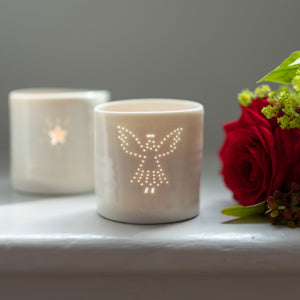 A photo of a ceramic porcelain tealight candle holder with a delicately pierced design of an angel. Homeware.