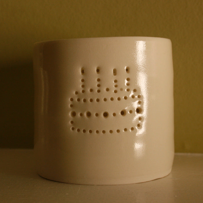 Porcelain ceramic tealight candle holder, featuring a design of a birthday cake with candles, natural glossy glaze. Unlit. Birthday present. Celebration.