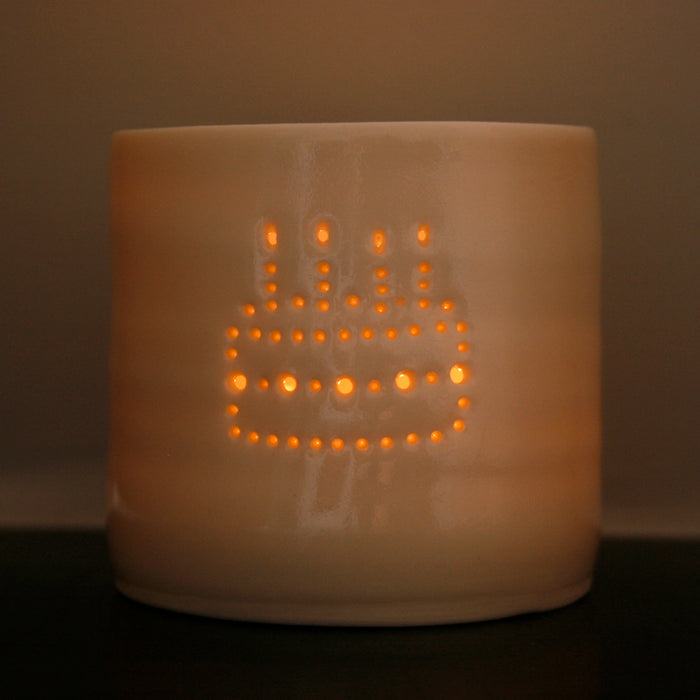 Porcelain ceramic tealight candle holder, featuring a design of a birthday cake with candles, natural glossy glaze. Birthday present. Celebration.