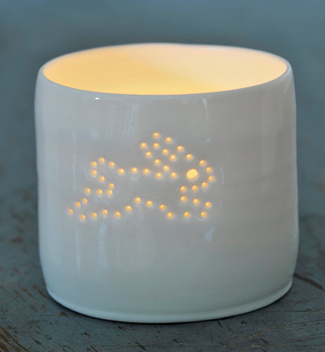Ceramic porcelain tealight candle holder, with a running bunny rabbit design pierced with tiny holes, allowing the candlelight to flicker through. New baby gift.