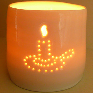 A porcelain ceramic tealight candle holder, votive, with an old fashioned candle holder design pierced into it using tiny holes. Natural glossy glaze. Homeware.
