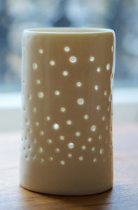 A porcelain ceramic tealight candle holder, votive, with a design of rising bubbles, like champagne. Natural glossy glaze.