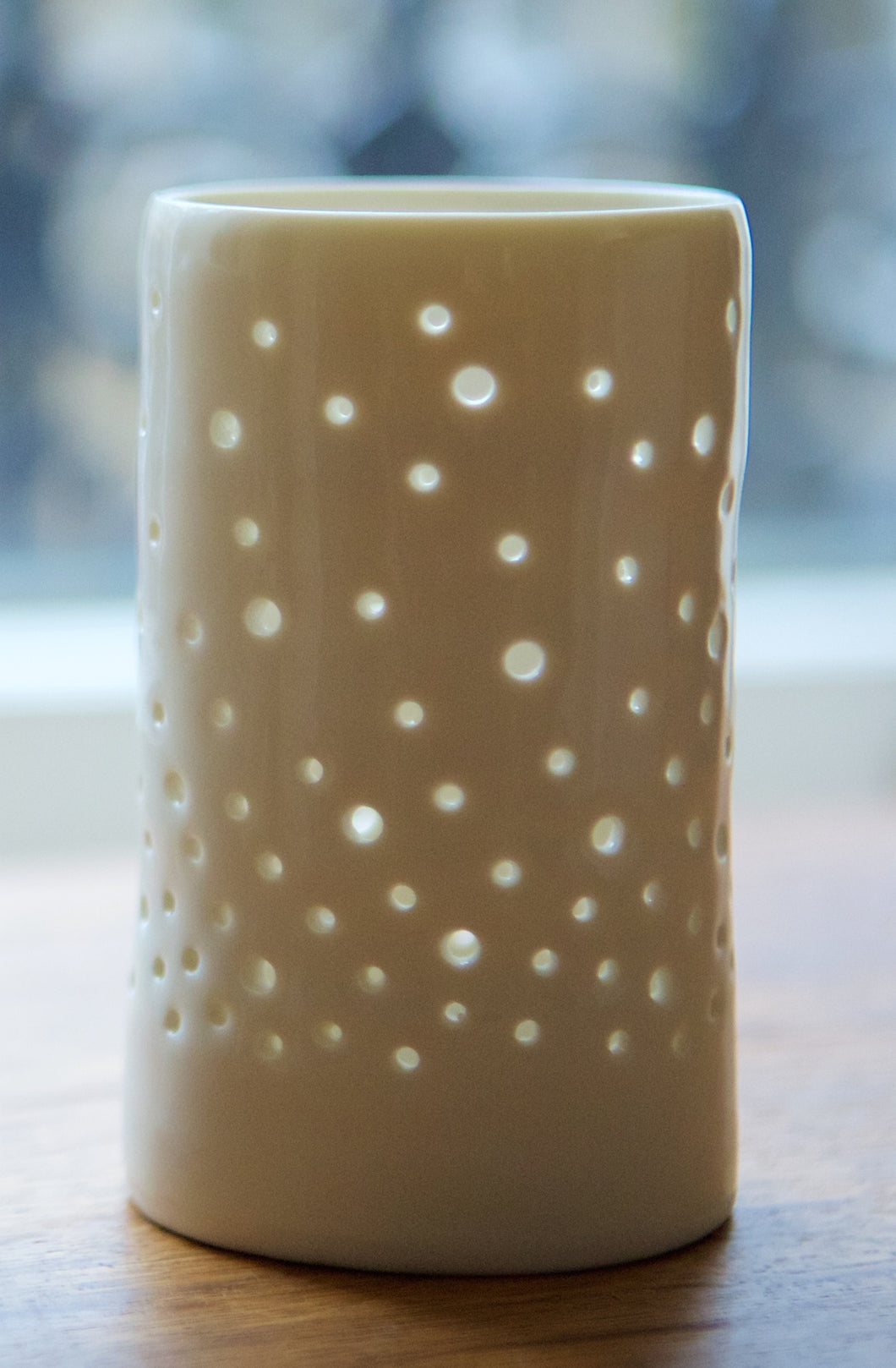 A porcelain ceramic tealight candle holder, votive, with a design of rising bubbles, like champagne. Natural glossy glaze.