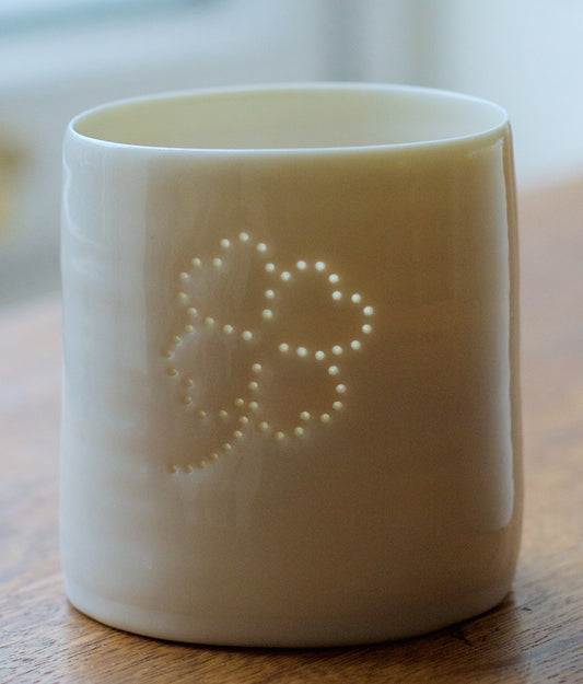 Ceramic porcelain tealight candle holder, featuring a design of a lucky four leafed clover. Tiny holes let the light shine through.