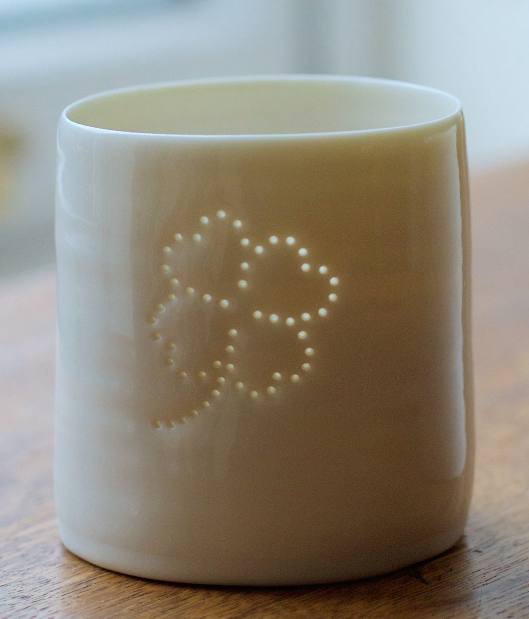 Ceramic porcelain tealight candle holder, featuring a design of a lucky four leafed clover. Tiny holes let the light shine through.