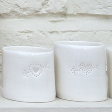 Load image into Gallery viewer, Two ceramic porcelain tealight holders, with a cupids heart pierced into it with tiny holes, allowing candlelight to twinkle through. The tealight holder has natural glossy glaze and is almost translucent. Relaxing homeware. Romantic gift.

