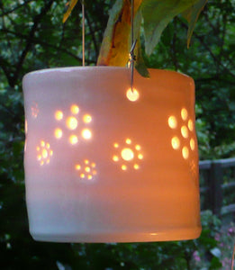 A natural porcelain ceramic tealight candle holder, with a floral design, resembling a field full of flowers. Garden decoration. Outdoor lighting.