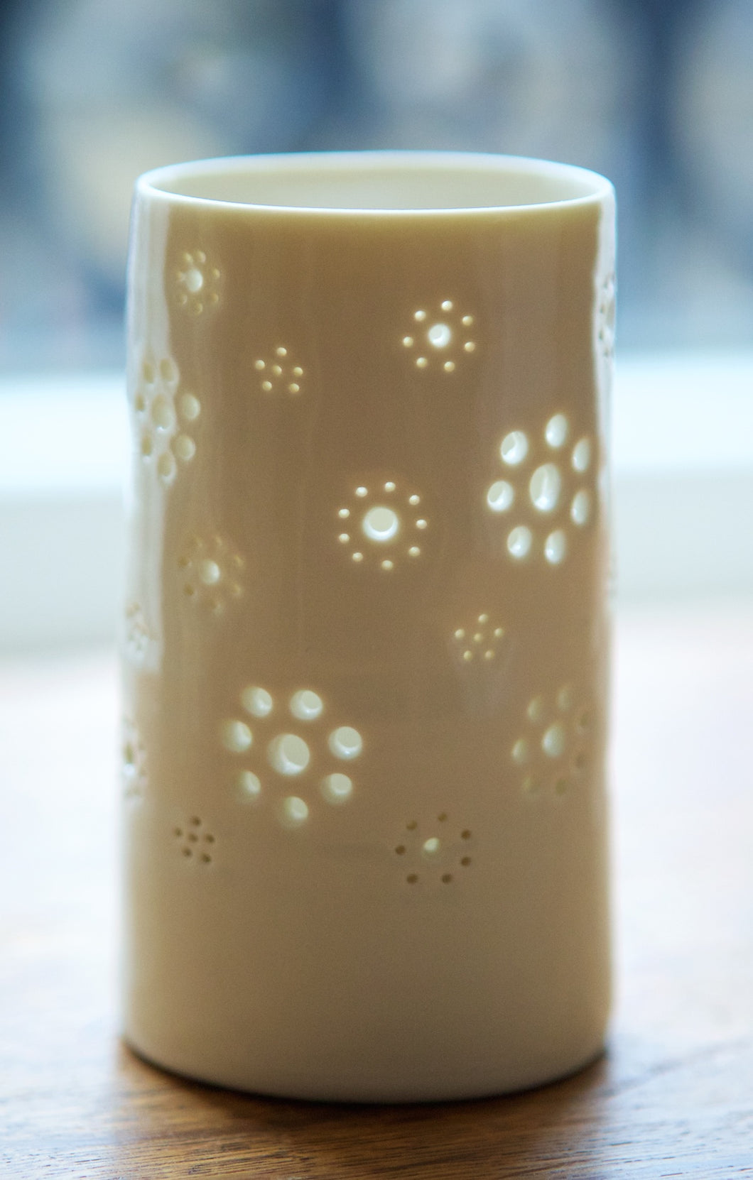 A natural porcelain ceramic tealight candle holder, with a floral design, resembling a field full of flowers.