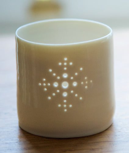 Porcelain ceramic tealight candle holder, glazed in a natural glossy glaze, and pierced with a snowflake design. Christmas gift. Decoration.