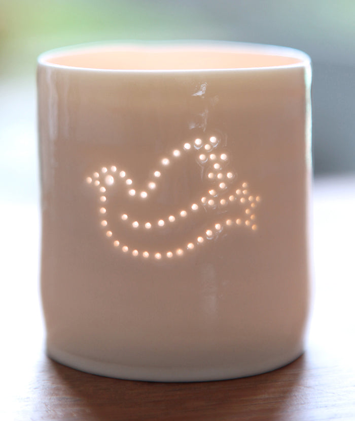 Symbol of peace, this porcelain tealight holder features a dove. Ceramic candle holder with a natural glossy glaze and gentle glow. Christmas decoration.