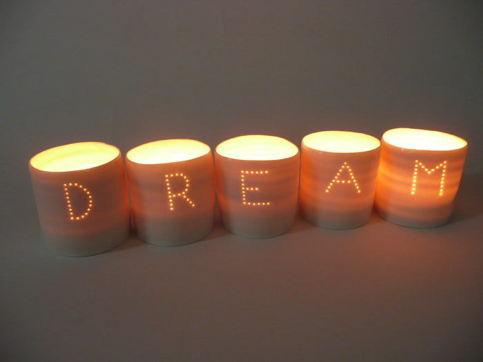 A series of five handmade porcelain tealight holders. These ceramic candle holders spell out the word "dream". Small business. Relaxing candles.