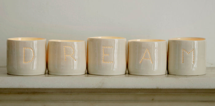 A series of five handmade porcelain tealight holders. These ceramic candle holders spell out the word "dream". Small business. Relaxing candles.