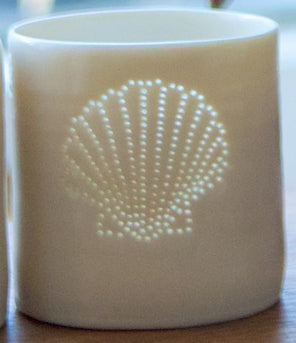 Ceramic tealight holder, this porcelain candle holder features a design of a shell. Natural glossy glaze, the light shines through the tiny holes to create a glow. Seaside.