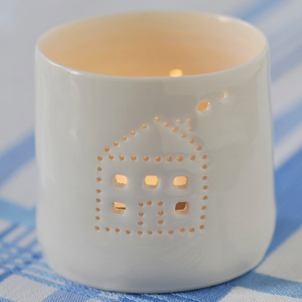 A cute house with smoke emerging from the chimney, pierced into a ceramic porcelain tealight candle holder. This candle votive will create a sense of home, hygge and warmth.
