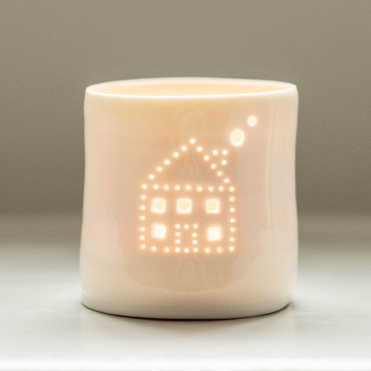 A sweet little house with smoke emerging from the chimney, pierced into a ceramic porcelain tealight holder. This candle votive will create a sense of home, hygge and warmth.