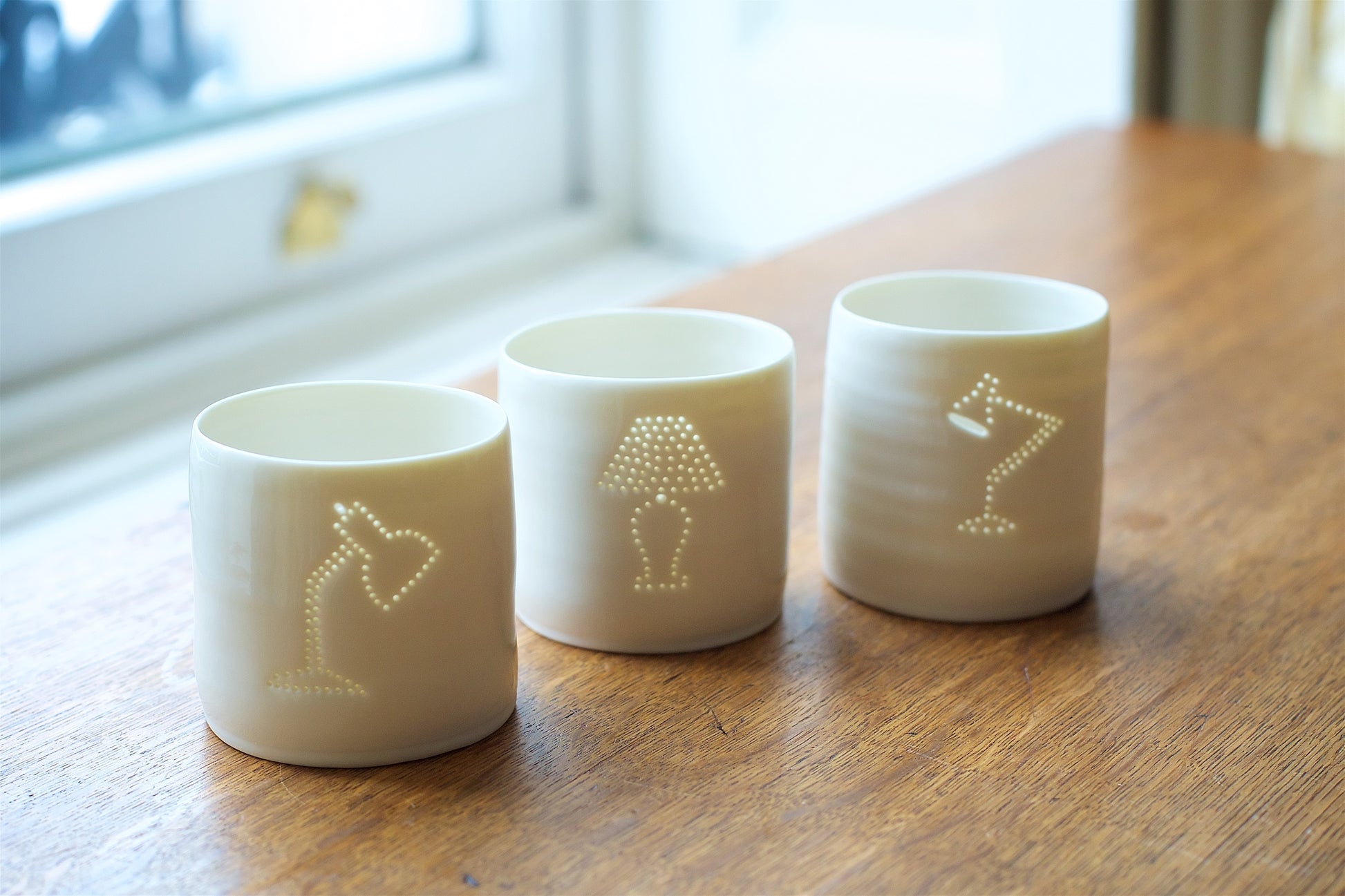 Three porcelain ceramic tea light holders, each with a design of a different classic lamp. Design classics from the midcentury.