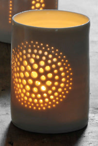 A natural porcelain ceramic tealight candle holder, with a floral design, resembling a large flower, like a dandelion. Homeware and garden decoration. Porcelain tableware. Also looks like a firework, concentric circles.