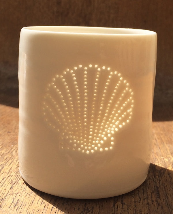 Ceramic tealight holder, this porcelain candle holder features a design of a shell. Natural glossy glaze, the light shines through the tiny holes to create a glow. Seaside.
