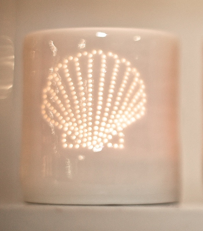 Ceramic tealight holder, this porcelain candle holder features a design of a shell. Natural glossy glaze, the light shines through the tiny holes to create a glow. Seaside.