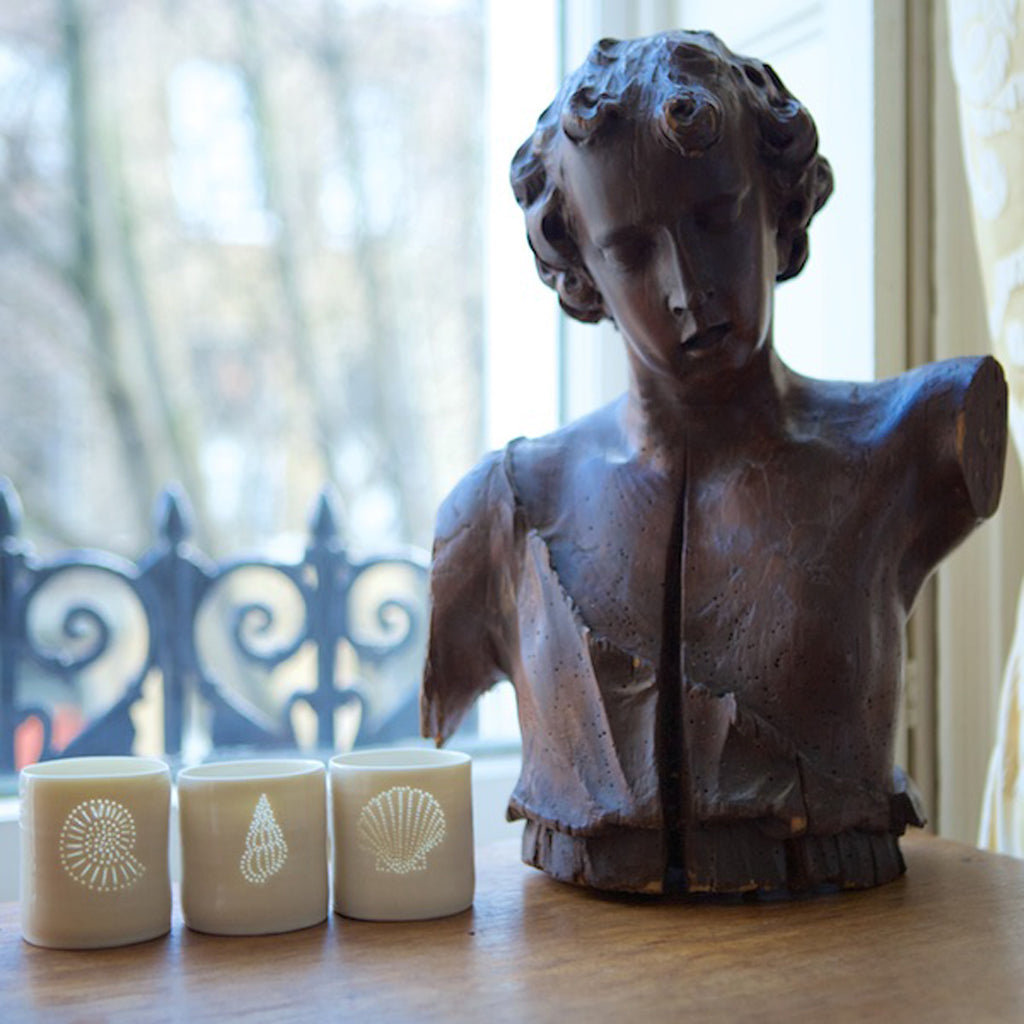 A trio of ceramic tealight holder, this porcelain candle holder features a design of a shell. Natural glossy glaze, the light shines through the tiny holes to create a glow. Seaside.
