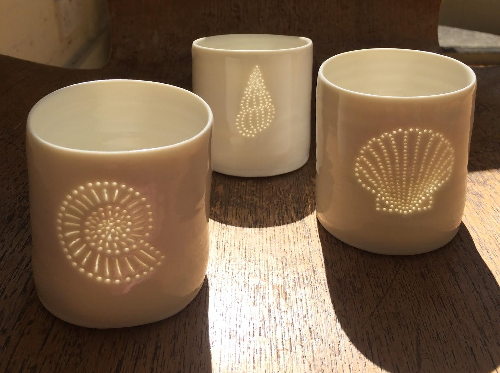 Three ceramic porcelain tealight candle holders, featuring different shell designs. Homeware for relaxing and creating a calm atmosphere. Celebrate a seaside holiday.