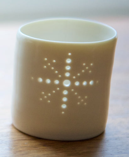 Porcelain ceramic tealight candle holder, glazed in a natural glossy glaze, and pierced with a snowflake design. Christmas gift. Decoration.