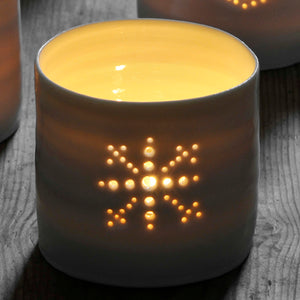 Porcelain ceramic tealight candle holder, glazed in a natural glossy glaze, and pierced with a snowflake design. Christmas gift. Decoration.