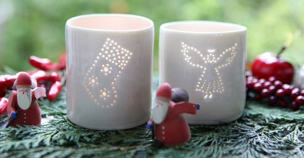 A photo of two ceramic porcelain tealight candle holders, one with an angel and one with a Christmas stocking