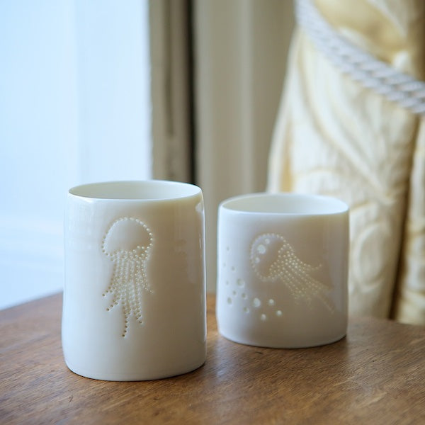Porcelain candle holder with delicate jellyfish design pierced into it. Candlelight flickers through the holes. Ceramic tealight holder for seaside holidays.